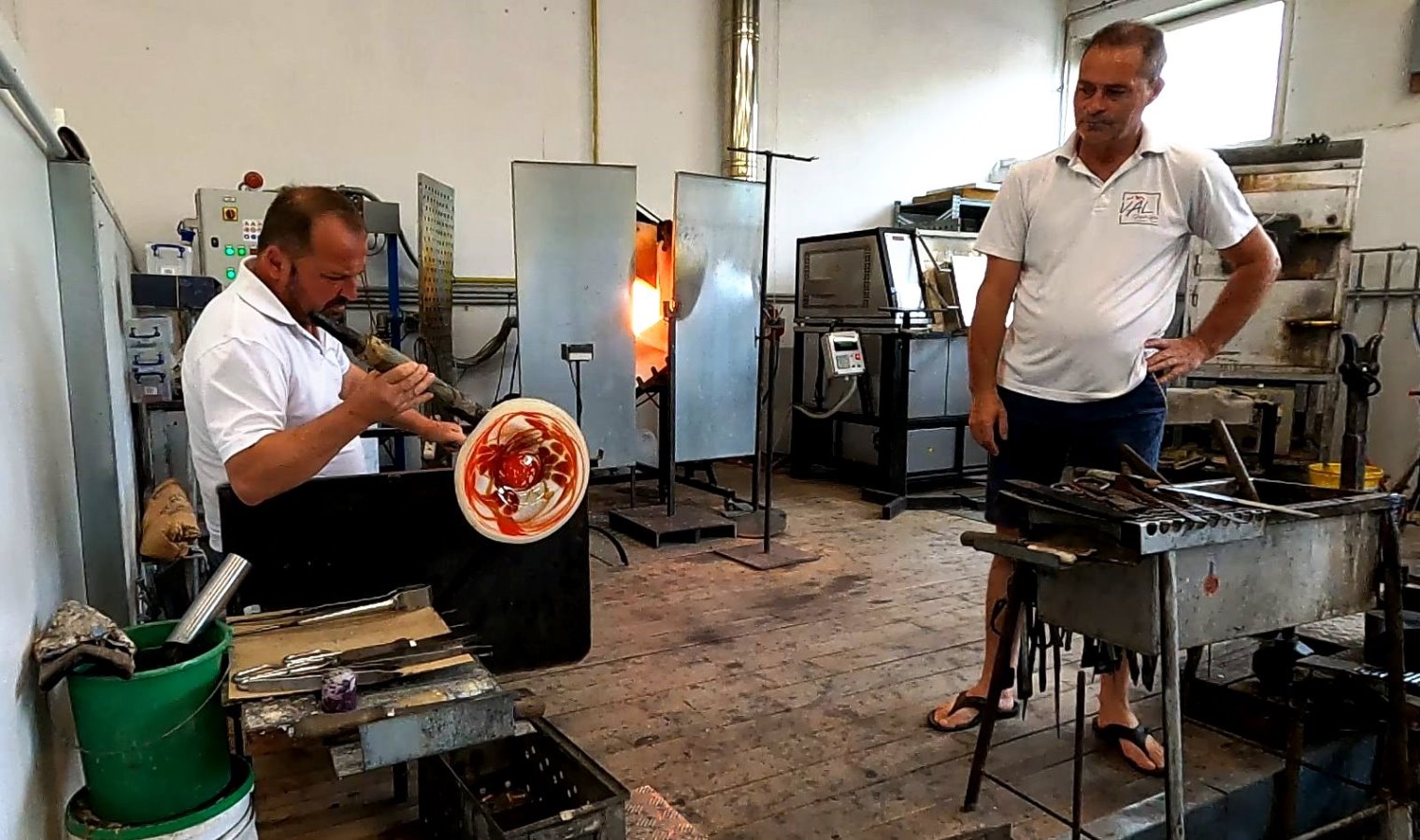 Ein Glasteller wird geformt - die Glasmasse glüht rot