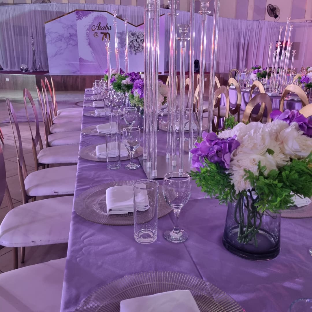 Man in a suit standing beside a dining table with floral decorations and a 'Hello Cavans' backdrop.