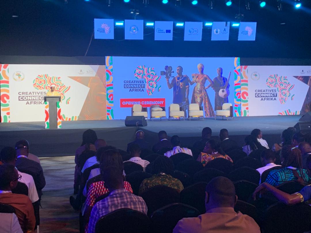 Smiling person with glasses wearing a light purple shirt indoors.