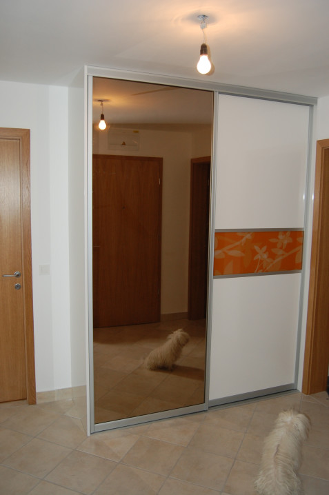 Vgradna omar z drsnimi vrati s kombinacijo ogledala in stekla. Leseni del je v beli barvi visok sijaj.