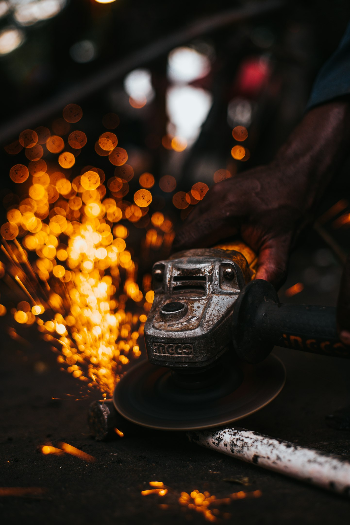 Welder wearing protective gear working with sparks in a metal workshop