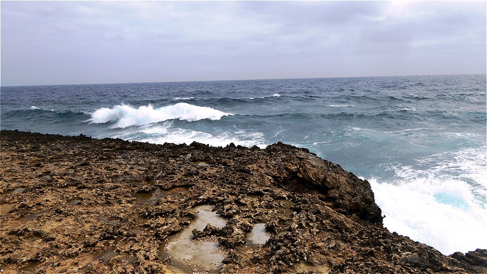 Die Wellen branden gegen die scharfen Korallenfelsen
