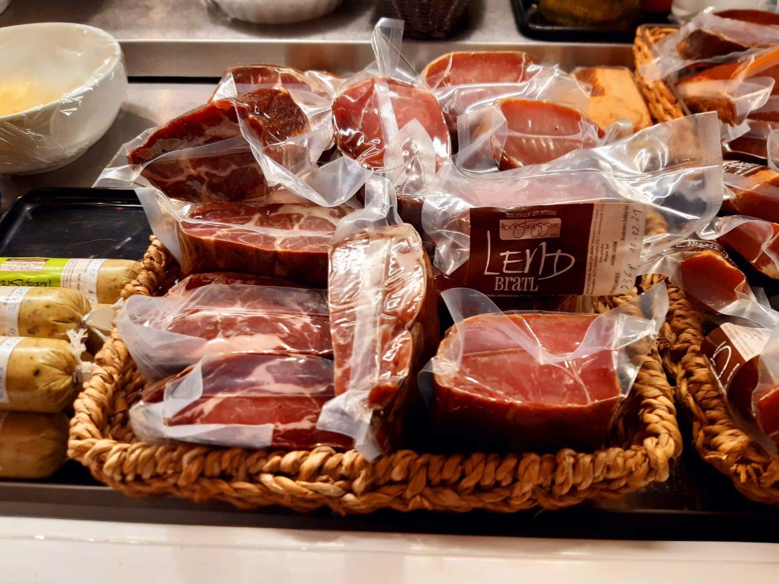 Vakuumverpacktes Fleisch in einem geflochtenen Korb auf einem Markt.