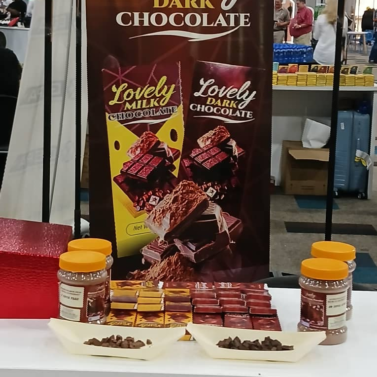 Two tins of cocoa powder with artistic labeling, surrounded by cocoa beans and leaves, showcasing the Rhundou brand.