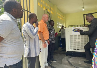 Young girl wearing a face mask in a classroom setting, looking attentively at another student.
