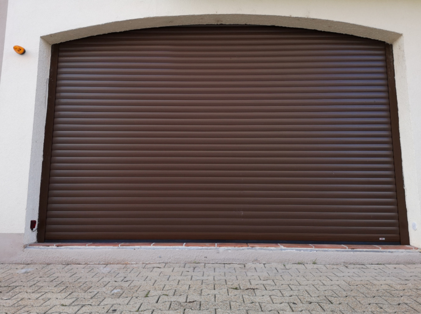 Porte de garage enroulable de marque LOUBAT FERMETURES avec grosses lames, cellule reflex et détecteur de passage infrarouge