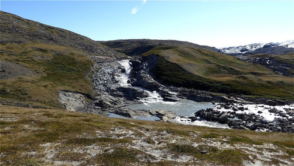 Schmelzwasser fällt über Felsstufen hinunter ins Tal