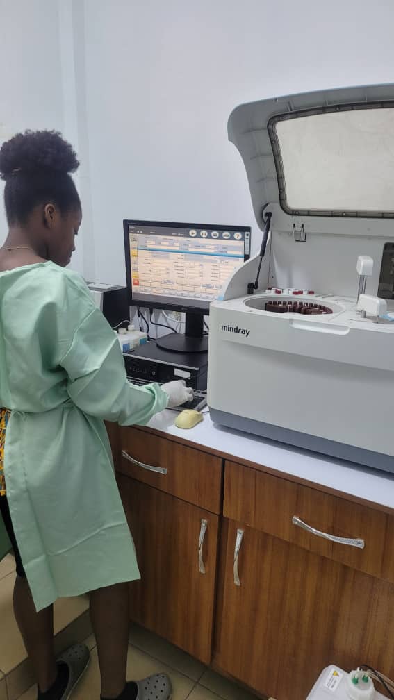 Modern laboratory with various equipment and chemical containers on shelves and workbenches, featuring computers and bright lighting.