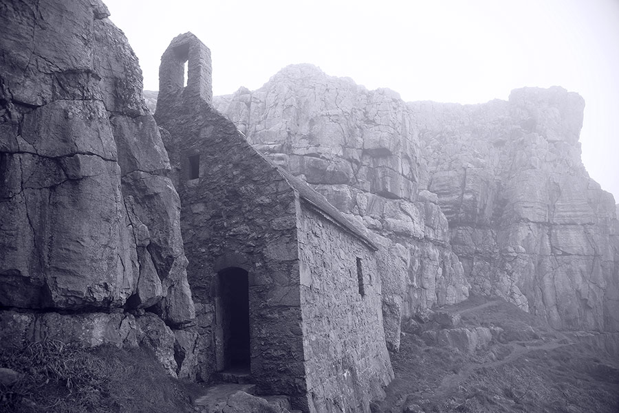 atmospheric black and white photograph of St. Govan's Chapel Pembrokeshire on a misty day by Mark Lloyd Williams