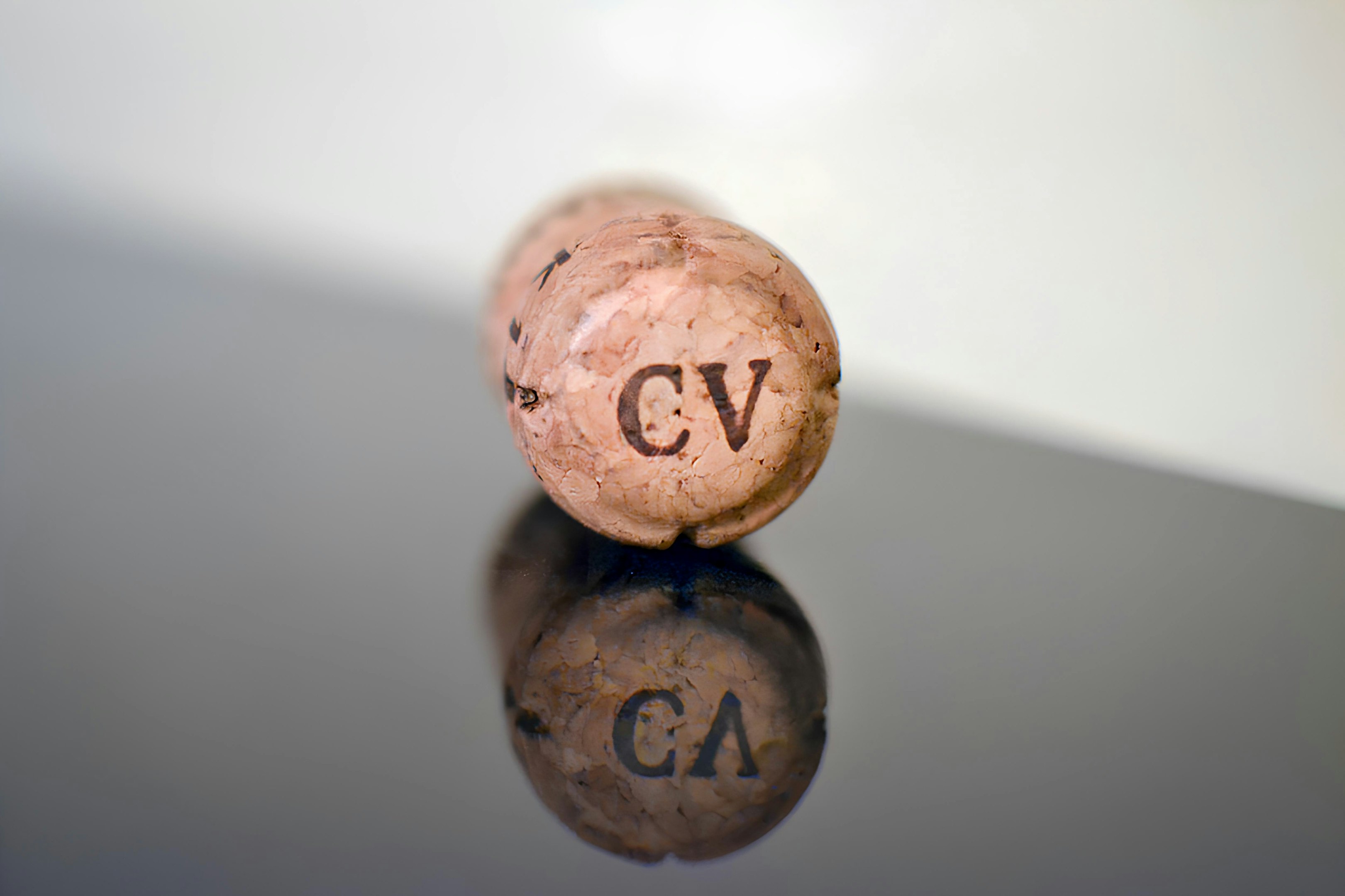 Cork from a bottle on a reflective surface with the word CV imprinted on the cork