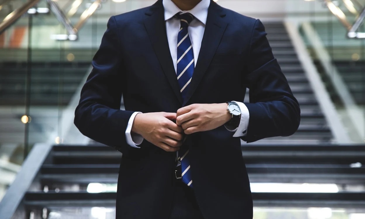 Business building and a smiling businessman drinking coffee in front of a laptop