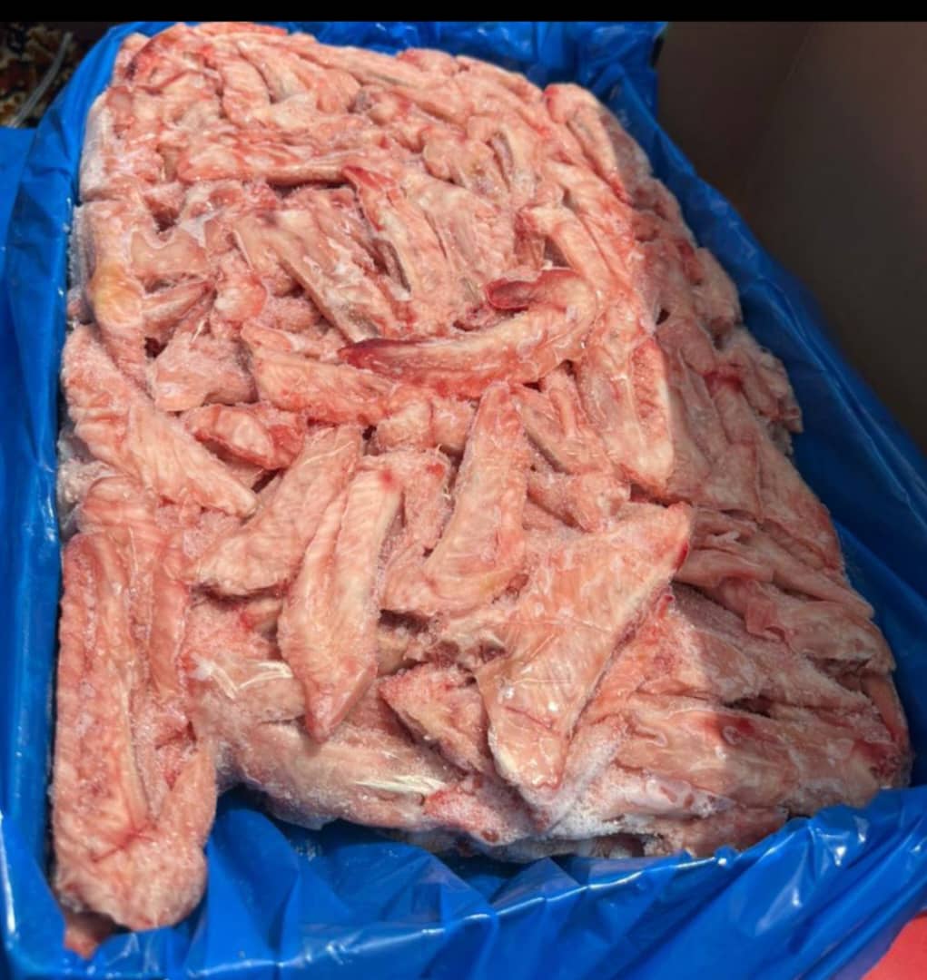 Sliced raw ham with sea salt on a slate platter, garnished with fresh herbs and served with a side bowl of dipping sauce, placed on a rustic wooden table.