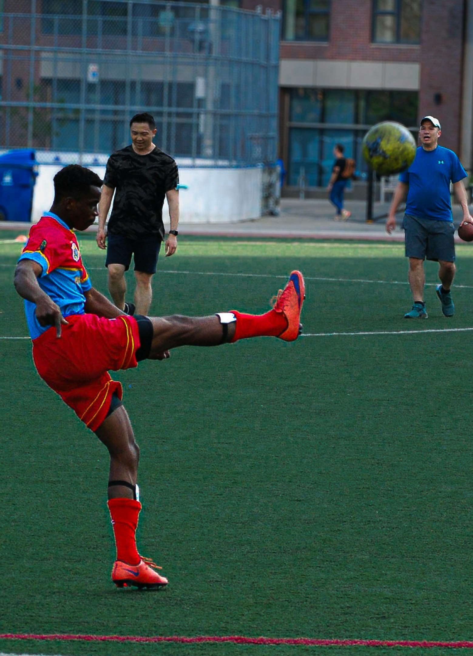 Group of young people in a casual office setting discussing around a table with a soccer ball, sign in background reads 'Prime Management Ghana'.