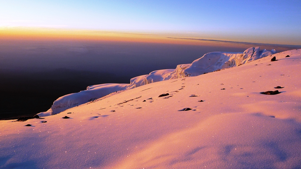Die aufgehende Sonne zaubert zarte Farben auf den Schnee