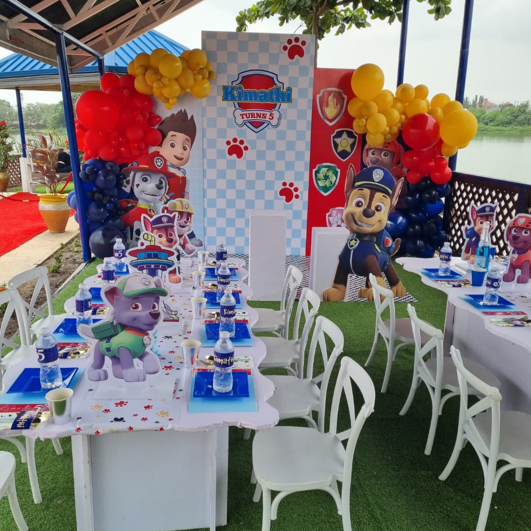 Elegant wedding stage decoration with round table, purple drapes, lush greenery, and floral arrangements under soft lighting.
