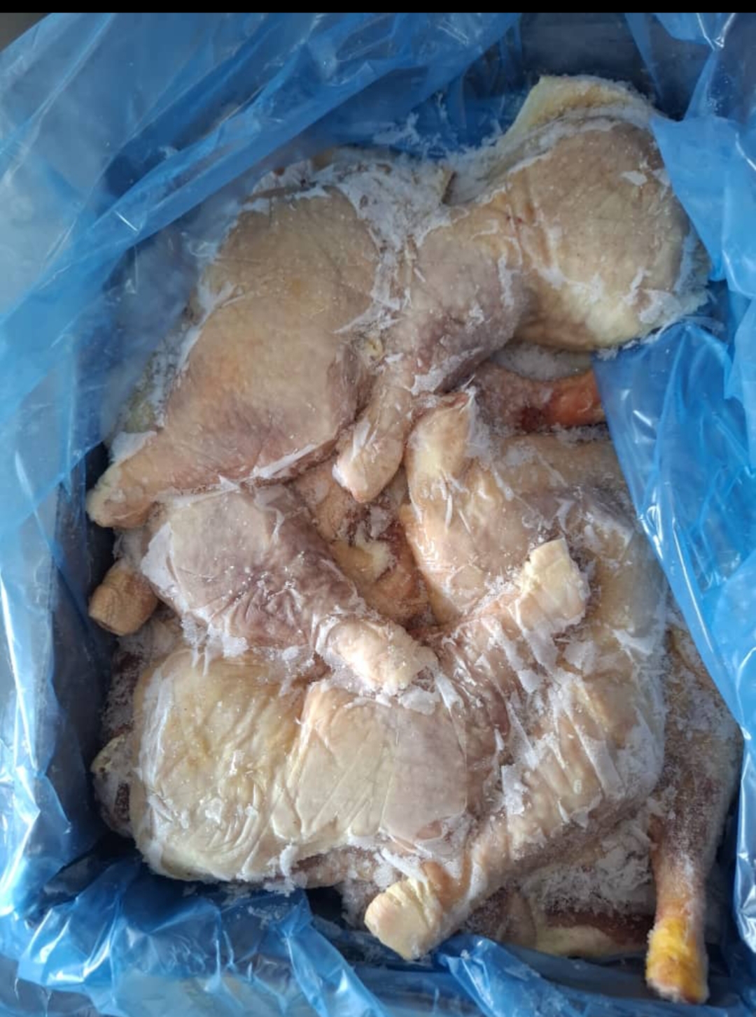 Fresh tuna slices on a wooden board with assorted vegetables, including tomatoes, broccoli, and garlic, in a kitchen setting.