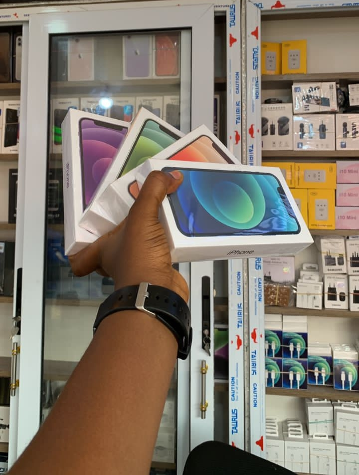 Modern building under construction with glass facade, surrounded by cranes and parked cars.
